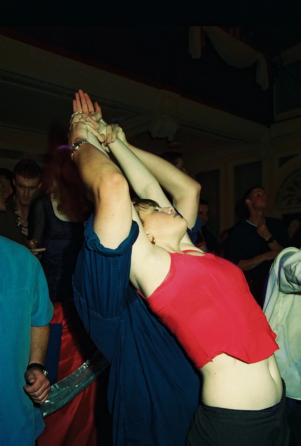 Temple Theatre, Dublin 2000. A dancer in a red top leans back in the crowd, arms stretched high overhead. 35mm photograph by Brendan Duffy.