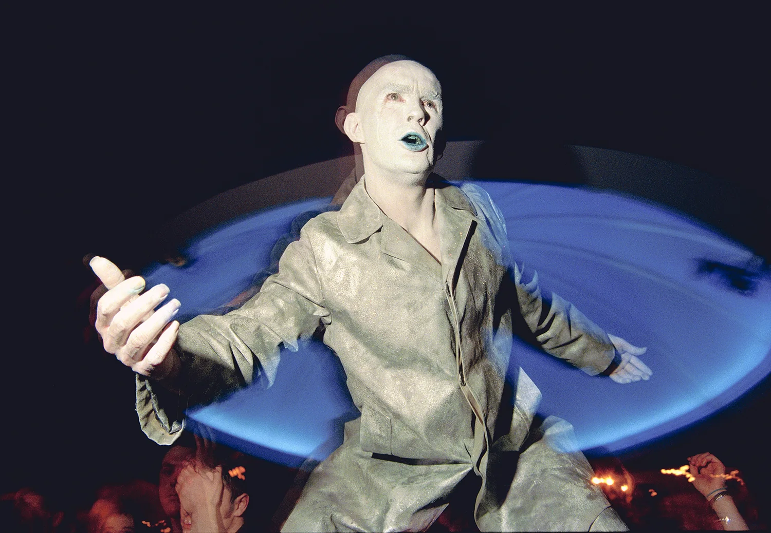 The Grill, Letterkenny, Co. Donegal 1999. A performer in white face paint and a grey suit spins in front of a blue light. 35mm photograph by Brendan Duffy.