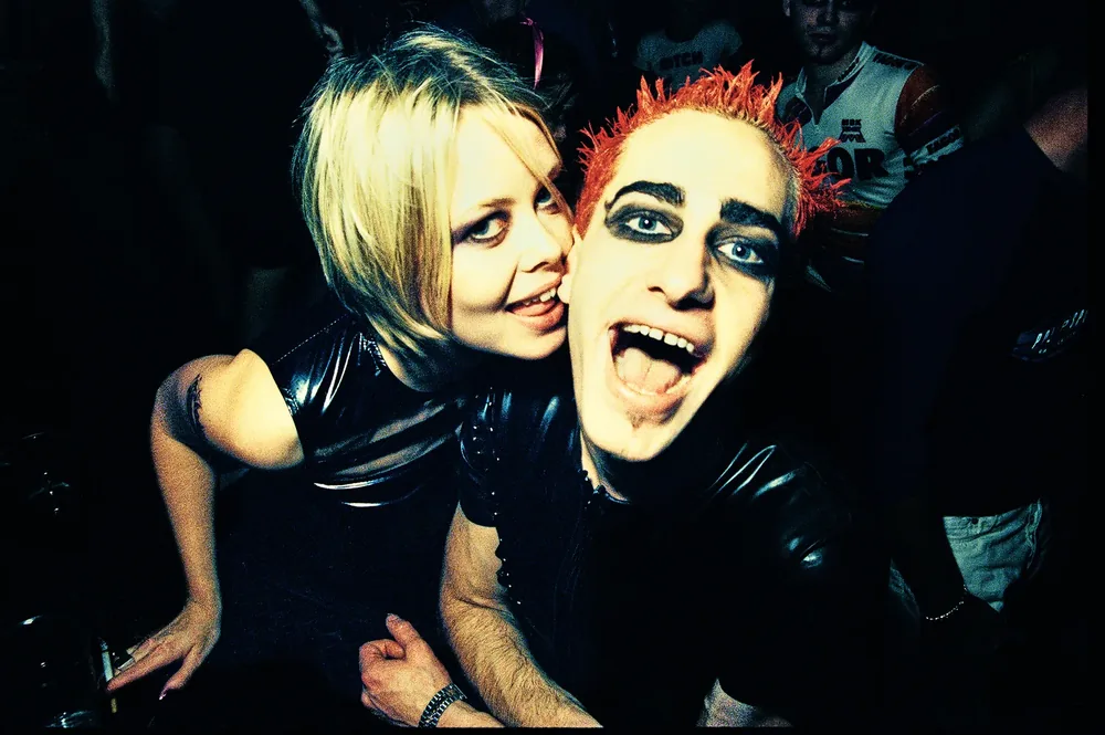 Powderbubble, Red Box, Dublin 1997. Two clubbers in black vinyl pull faces for the camera, one with spiked red hair and dark eye makeup. 35mm photograph by Brendan Duffy.