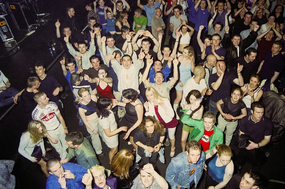 Red Box, Dublin 1998. The crowd seen from above, arms raised and pointing up at the camera. 35mm photograph by Brendan Duffy.