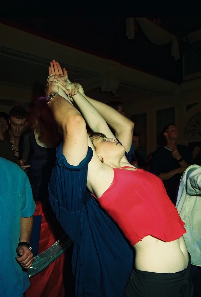 Temple Theatre, Dublin 2000. A dancer in a red top leans back in the crowd, arms stretched high overhead. 35mm photograph by Brendan Duffy.